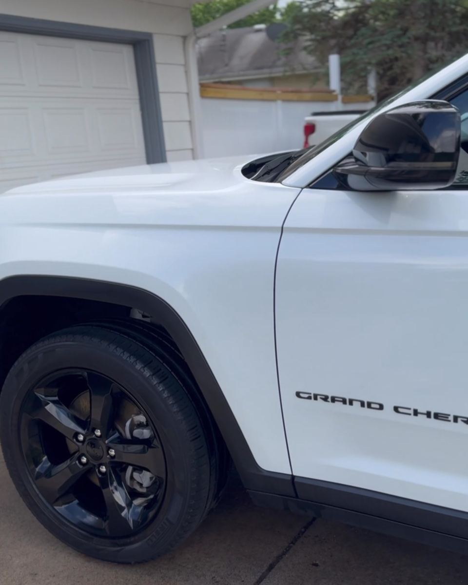 White Jeep Grand Cherokee in a driveway after a full detail, black wheels gleaming